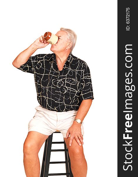 An senior in shorts sitting on a bar chair having a good coffee. An senior in shorts sitting on a bar chair having a good coffee.