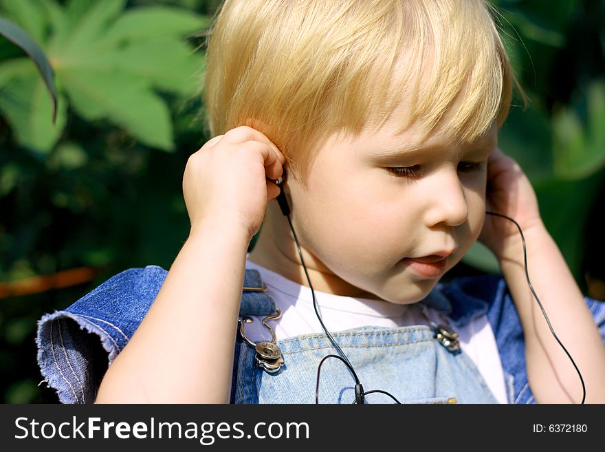 The child listens with pleasure to music in headphones. The child listens with pleasure to music in headphones