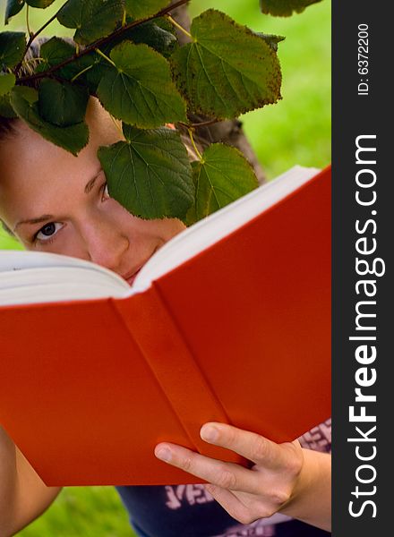 Portrait of pretty young woman with book under the tree