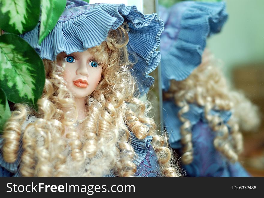 The beautiful doll with blue eyes sitting near mirror. The beautiful doll with blue eyes sitting near mirror