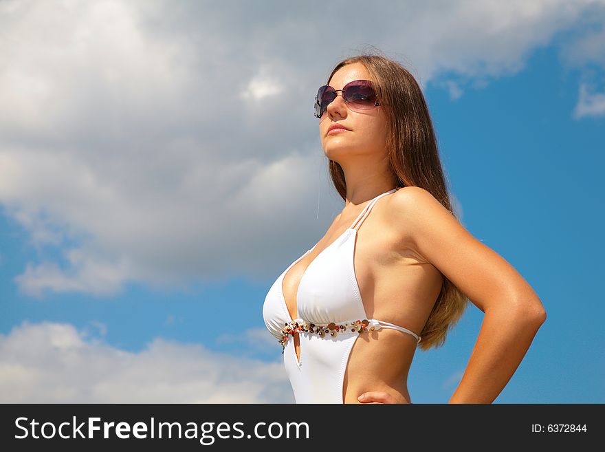 Girl in sunglasses in swimsuit against cloudy sky