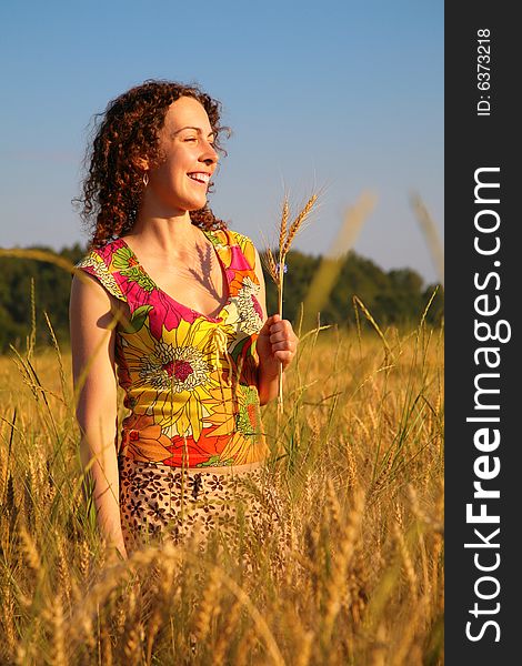 Young woman stands on wheaten field
