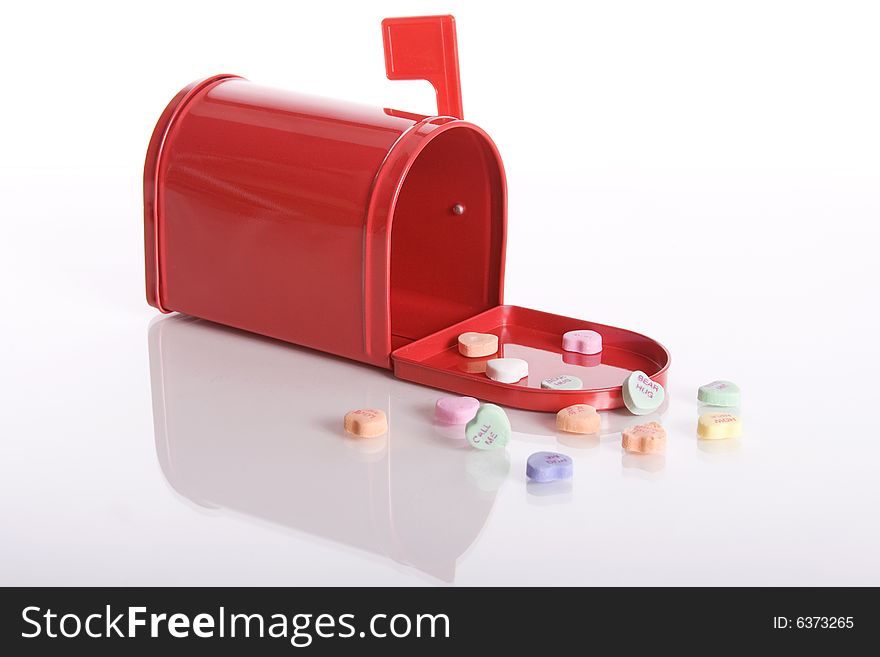 Red mailbox with candy valentine hearts lying in front of it against a white background. Red mailbox with candy valentine hearts lying in front of it against a white background