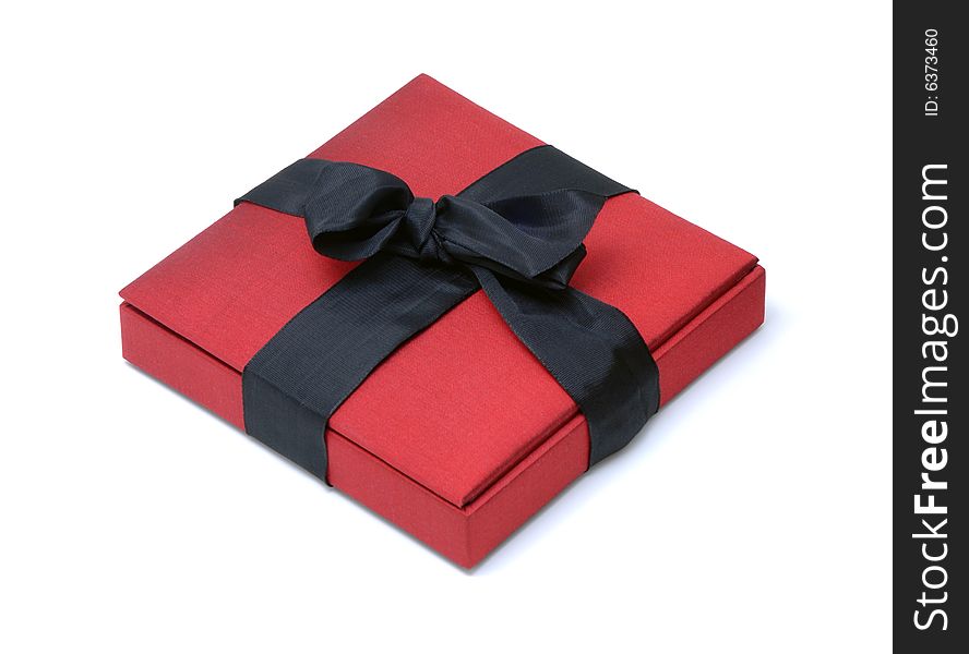 Red Silk Gift Box with a Black Ribbon Bow on an Isolated Background. Red Silk Gift Box with a Black Ribbon Bow on an Isolated Background