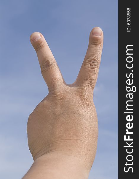 Victory symbol against blue sky