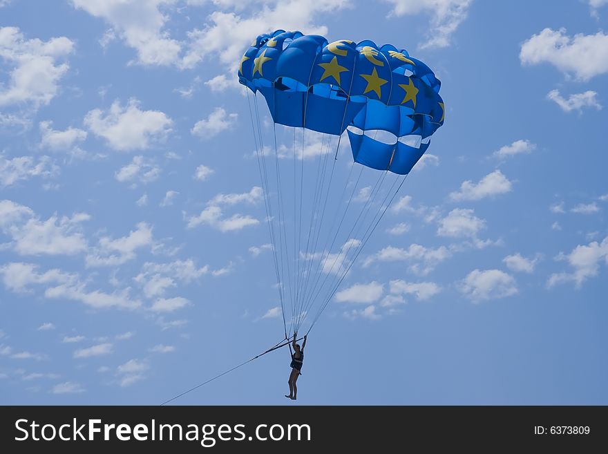 Man with a blue paraglider flying in the sky