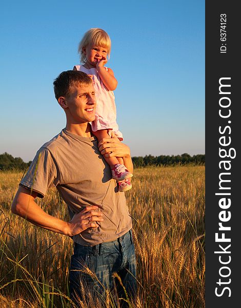 Father hold daughter on shoulder on wheaten field