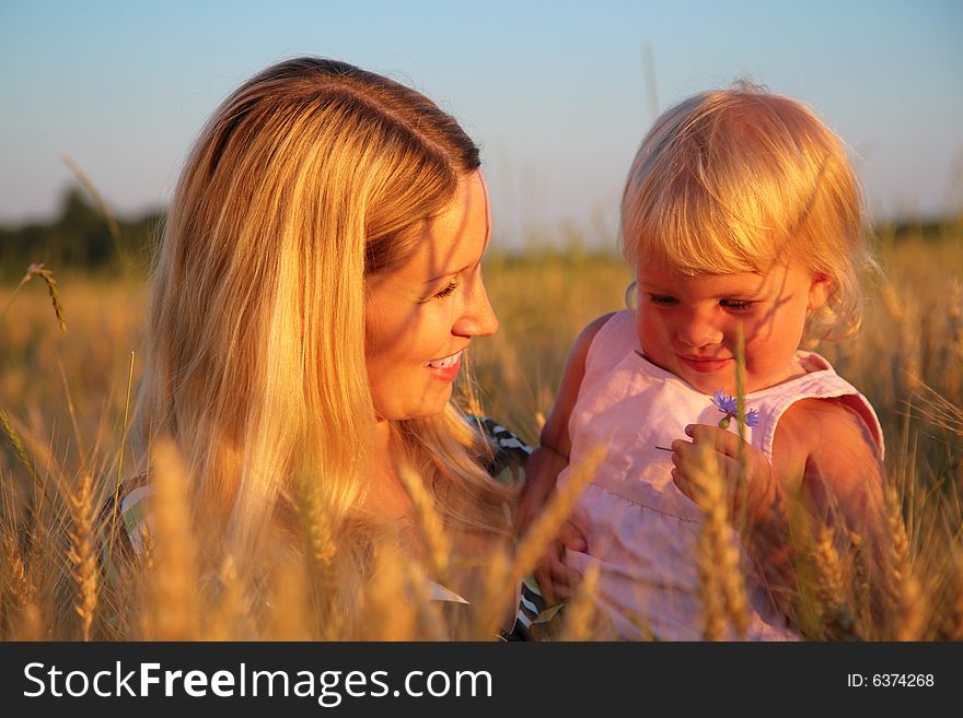 Mother with child sit in a wheaten field