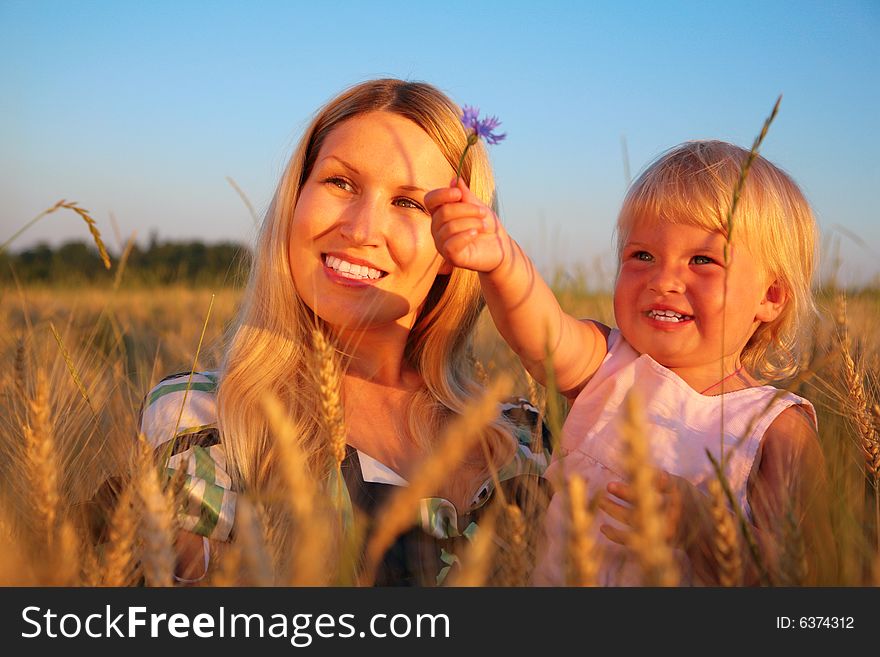 Mother With Child Sit In Wheaten Field With Cornf