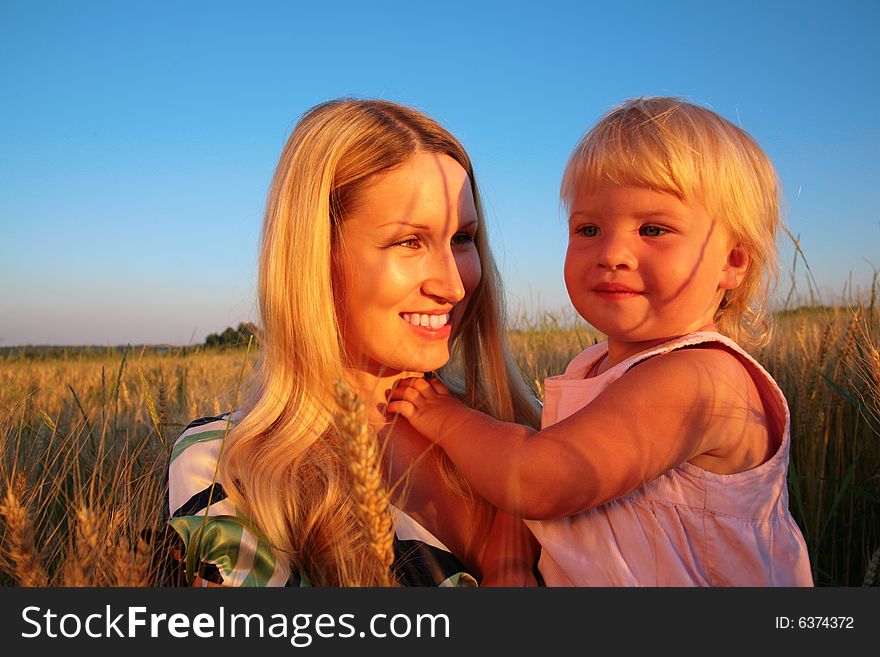 Mother and child  sit on a wheaten field