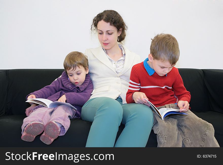 Children with mother read books on sofa