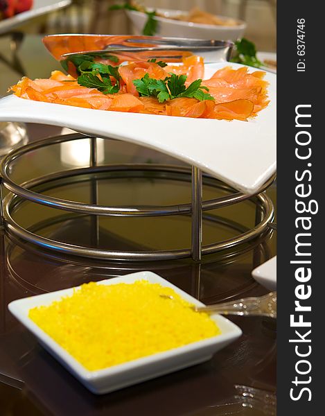 An image of decadent thinly sliced smoked salmon with garnish. An image of decadent thinly sliced smoked salmon with garnish