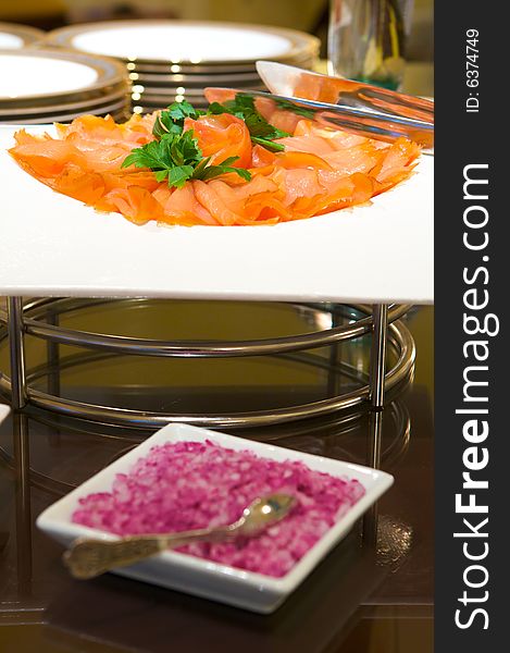 An image of decadent thinly sliced smoked salmon with garnish. An image of decadent thinly sliced smoked salmon with garnish