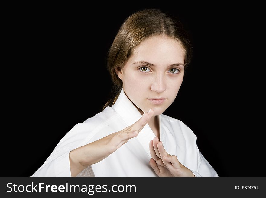 Pretty young girl in a karate pose on black background