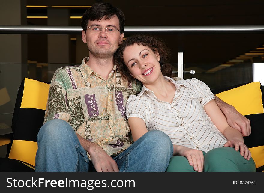 The couple sit on sofa in dark hall