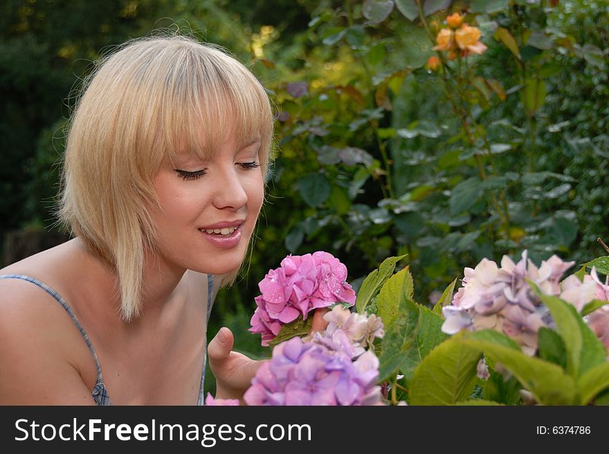 Young blond girl in garden smelling flower. Young blond girl in garden smelling flower
