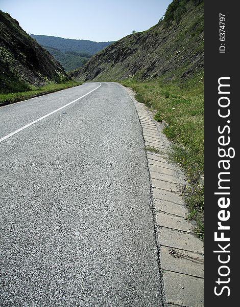 Empty road between two hills, left curve in distance