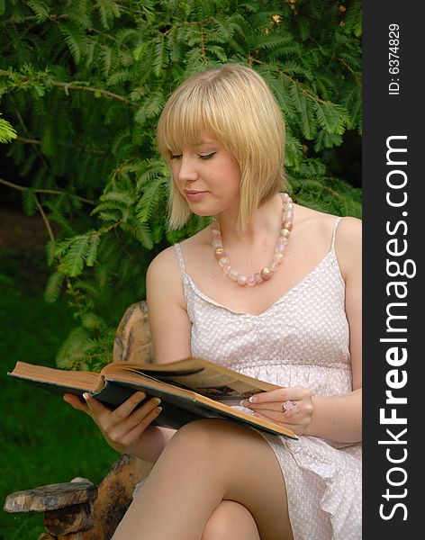 Cute blond reads book in garden