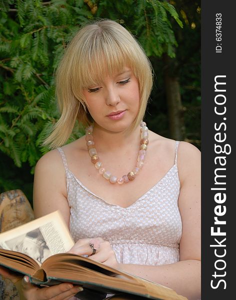 Cute Blond Reads Book In Garden