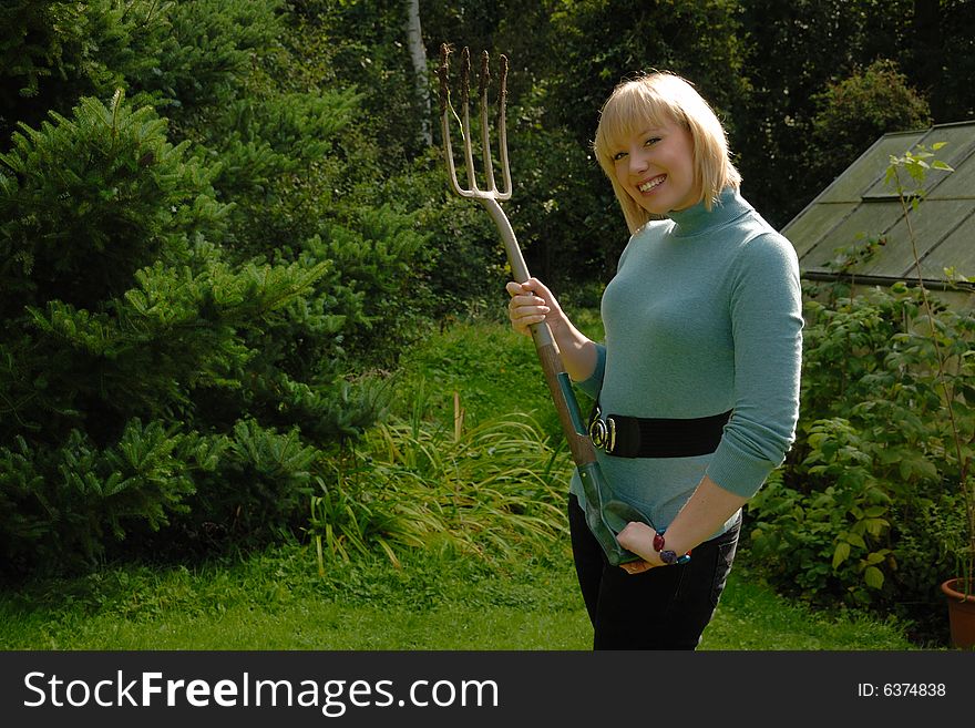 Attractive blond lady gardener smiling with fork. Attractive blond lady gardener smiling with fork