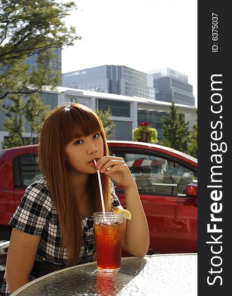 A young girl drinking lemon juice as she is sitting at a table outdoors. A young girl drinking lemon juice as she is sitting at a table outdoors.