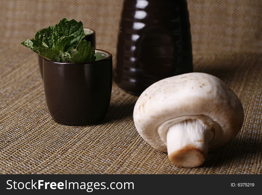 A mushroom beside a cup with other food ingredient. A mushroom beside a cup with other food ingredient