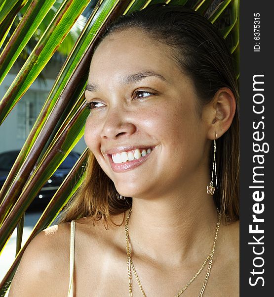 Young woman with a palm frond in the background. Young woman with a palm frond in the background.