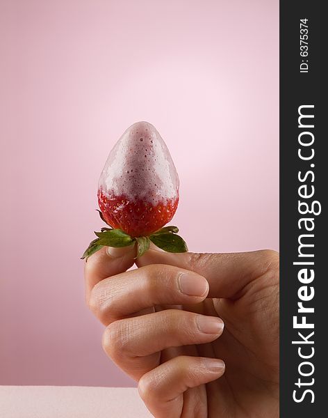 A lady's hand holding a strawberry