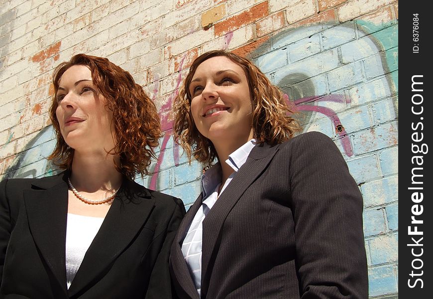 Two business women look to a point out of shot - taken outside