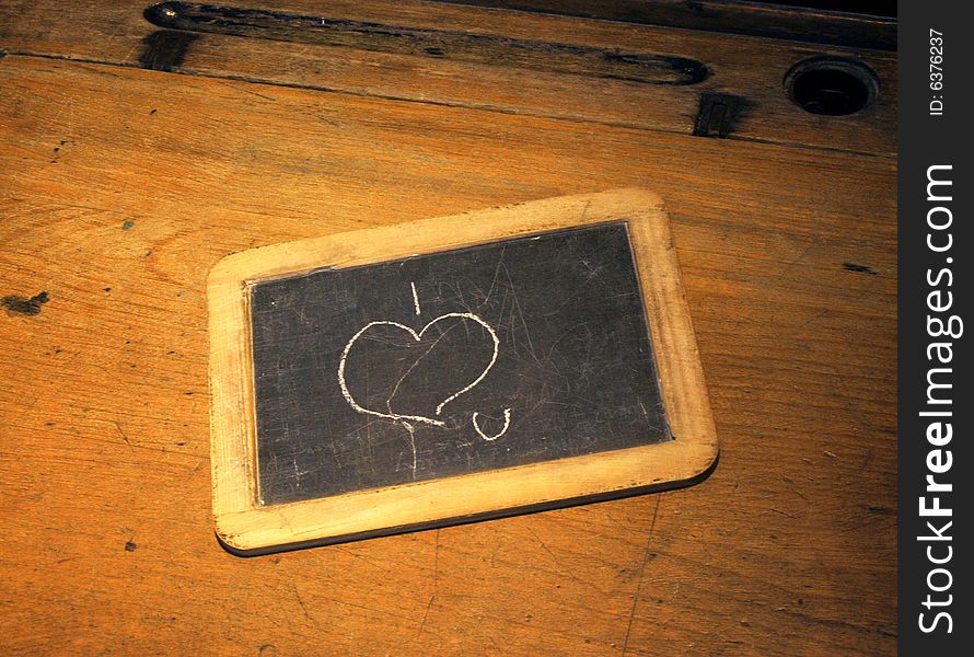 I love you scribbled on old blackboard resting on school desk. I love you scribbled on old blackboard resting on school desk