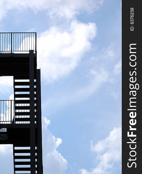 Silhouette of steel fire escape with cloudy ble sky