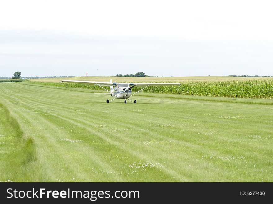 Image of a small aircraft landing on green field. Image of a small aircraft landing on green field