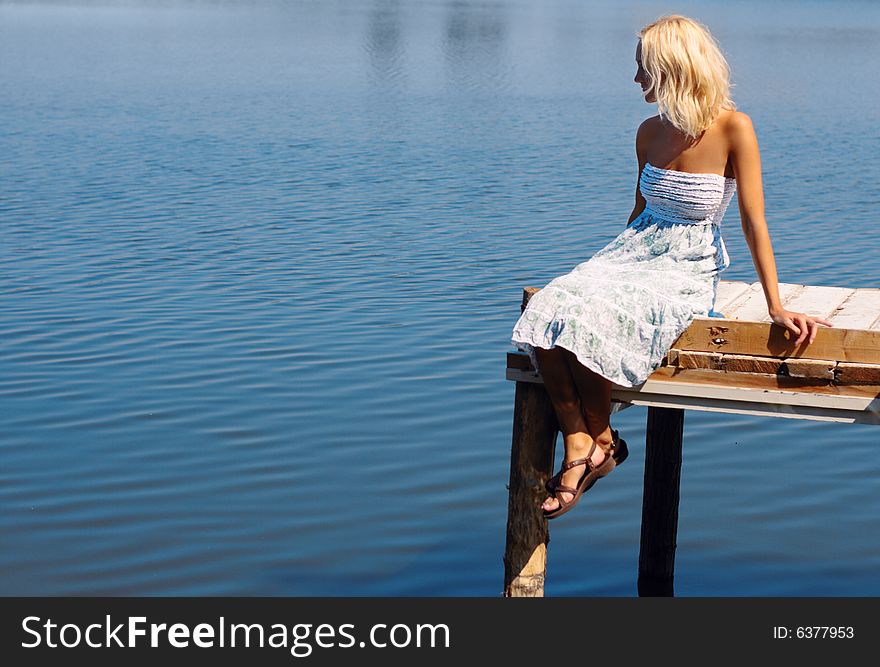 Girl sitting on a pier at the river bank, natural sun light