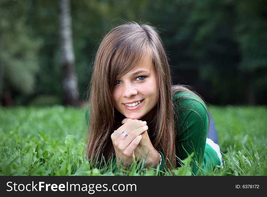 A picture of a girl, smiling to the camera being within the branches. A picture of a girl, smiling to the camera being within the branches