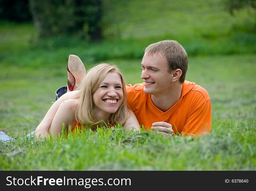 Loving couple lies and embraces on a green grass