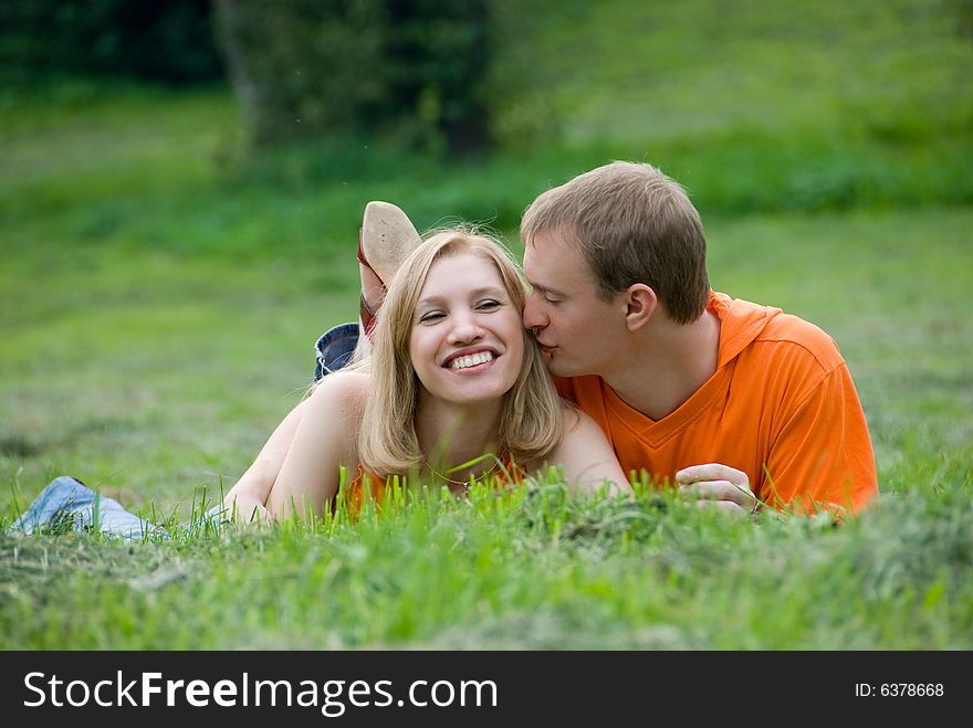 Loving couple lies and embraces on a green grass