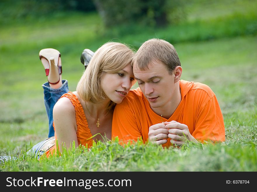 Loving couple lies and embraces on a green grass