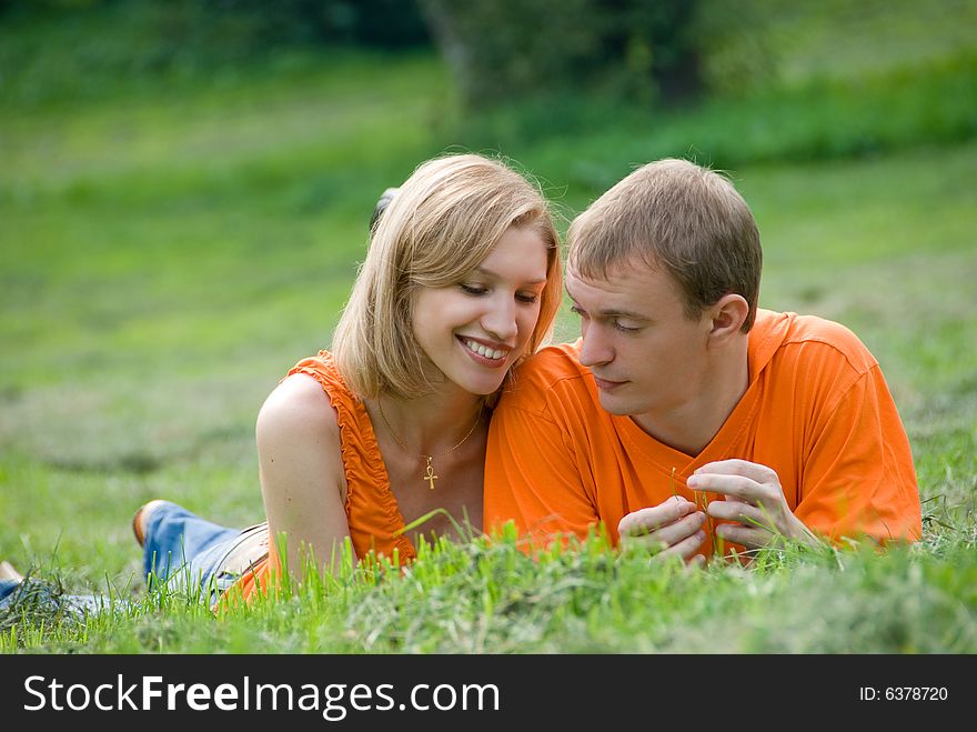 Loving couple lies and embraces on a green grass