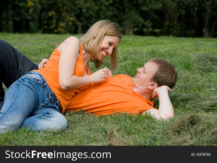 Loving couple lies on a green grass