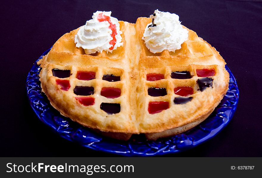 Waffle with cream and coating with chocolate and strawberry syrup