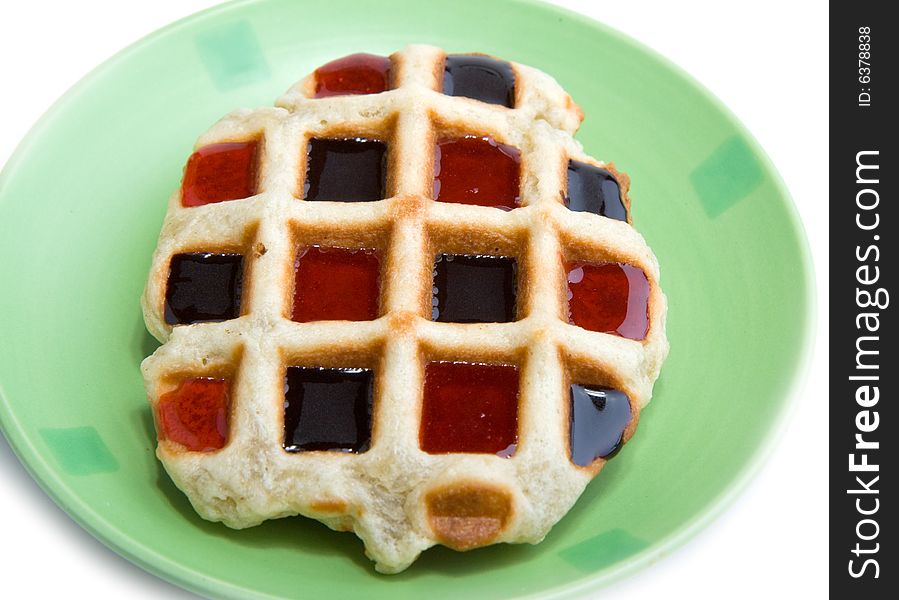 Waffle on green plate with cocolatte and strawberry coating. Waffle on green plate with cocolatte and strawberry coating