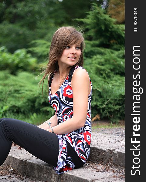 Portrait of a gorgeous girl looking at the right. She is dressed in a colorful, above the knees dress and jeans.