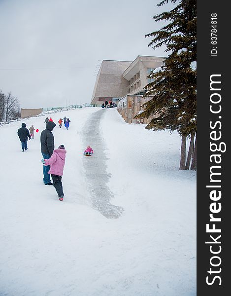 A laughing child sleds down a snow covered hill. A laughing child sleds down a snow covered hill.