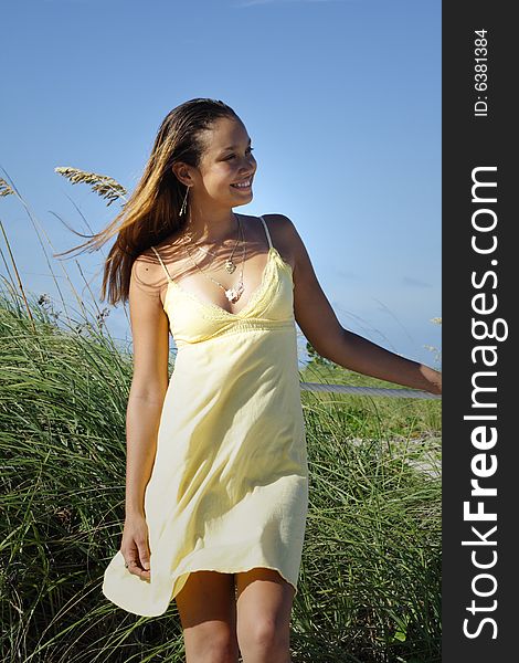 Young woman standing by sand dunes on the beach. Young woman standing by sand dunes on the beach.