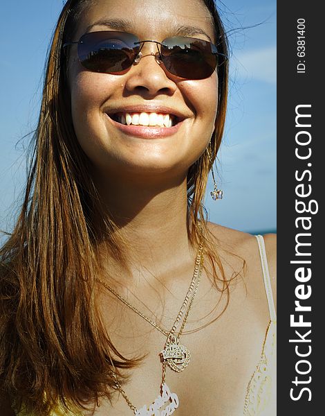 Woman smiling on a blue sky background. Woman smiling on a blue sky background