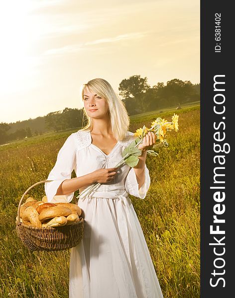 Beautiful young woman with a basket full of fresh baked bread. Beautiful young woman with a basket full of fresh baked bread