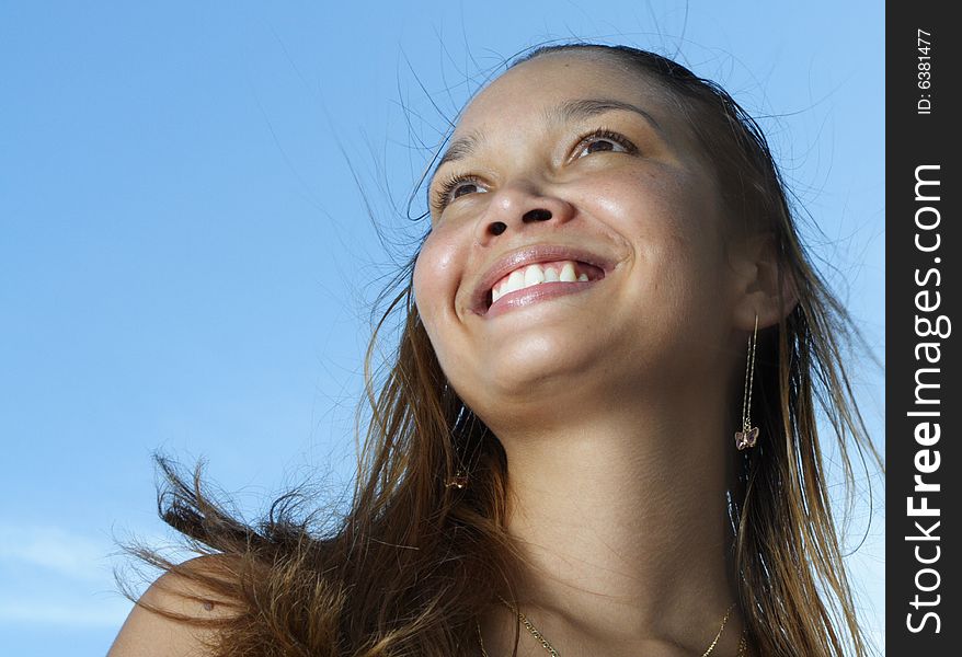 Young female smiling on a blue sky background. Young female smiling on a blue sky background