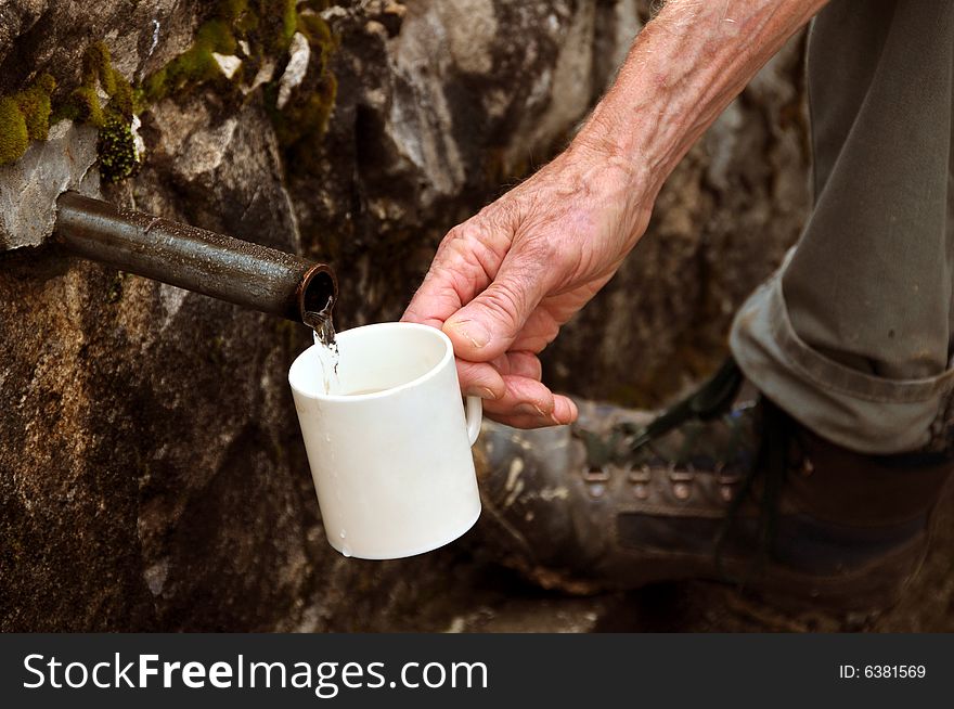 Old man hand filling a cup by water. Old man hand filling a cup by water