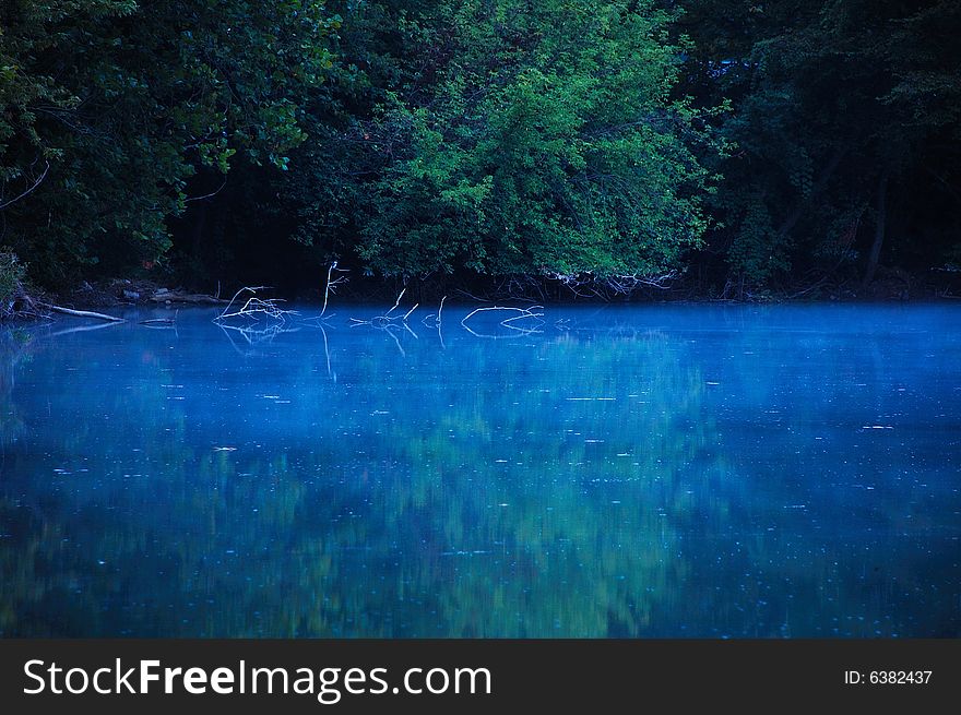 This is a early morning shot of a lake. The reflection of the tree line can be seen in the water. This is a early morning shot of a lake. The reflection of the tree line can be seen in the water.