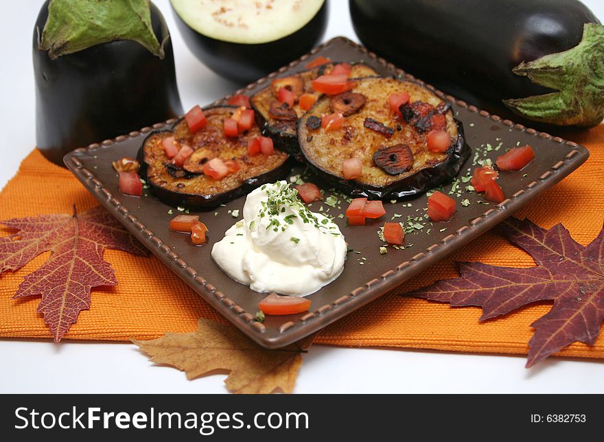 Some fresh aubergines with tomato-sauce on a plate